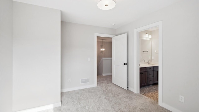 unfurnished bedroom featuring ensuite bath, light carpet, and sink