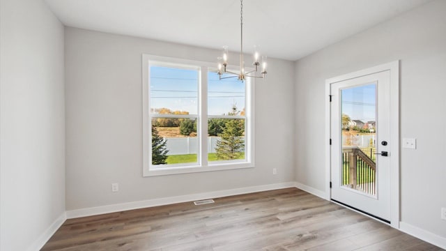 unfurnished dining area with light hardwood / wood-style flooring and a chandelier