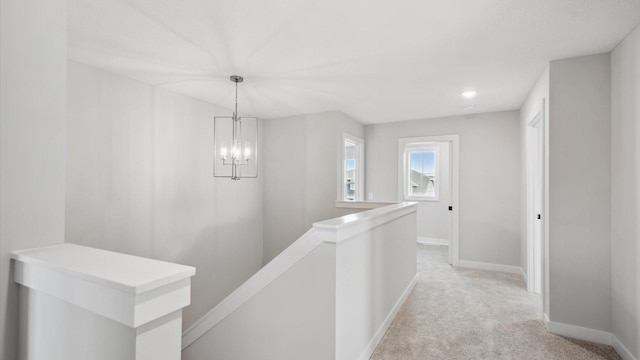 hall with a notable chandelier and light colored carpet