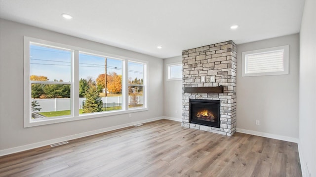 unfurnished living room with light hardwood / wood-style floors and a stone fireplace