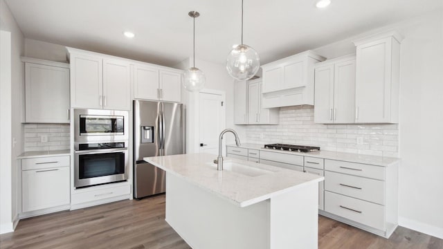 kitchen featuring stainless steel appliances, a kitchen island with sink, white cabinetry, and sink