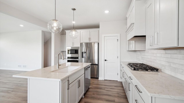 kitchen featuring decorative light fixtures, an island with sink, decorative backsplash, appliances with stainless steel finishes, and sink