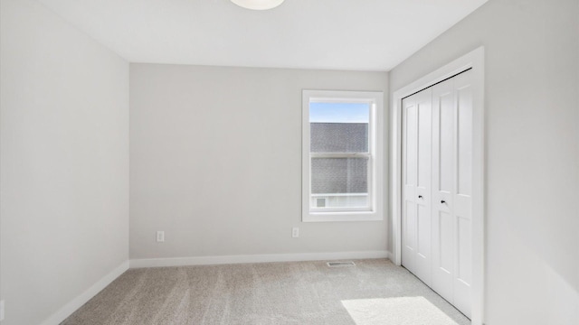 unfurnished bedroom featuring light colored carpet and a closet