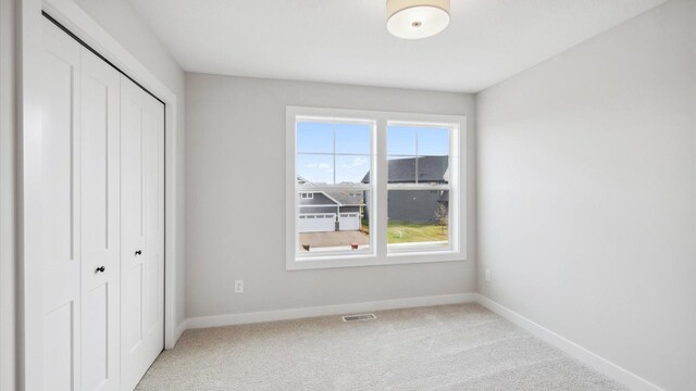 unfurnished bedroom with a closet and light carpet