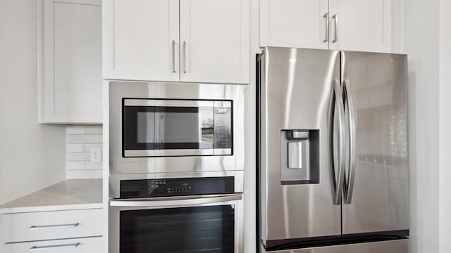 kitchen with light stone countertops, white cabinets, tasteful backsplash, and appliances with stainless steel finishes