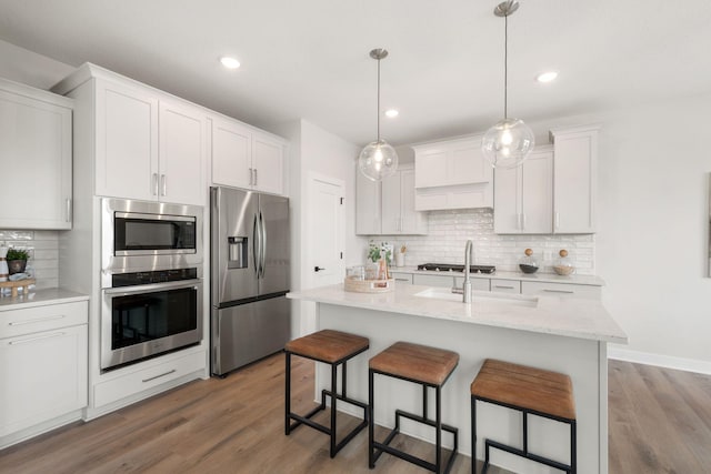 10238 Arrowwood Path, Woodbury, MN 55129 - kitchen with stainless steel appliances, decorative backsplash, a kitchen bar, wood finished floors, and white cabinetry