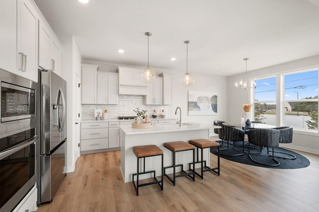10238 Arrowwood Path, Woodbury, MN 55129 - kitchen featuring stainless steel appliances, a kitchen bar, light wood finished floors, tasteful backsplash, and light countertops