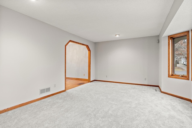 empty room featuring a textured ceiling and light carpet