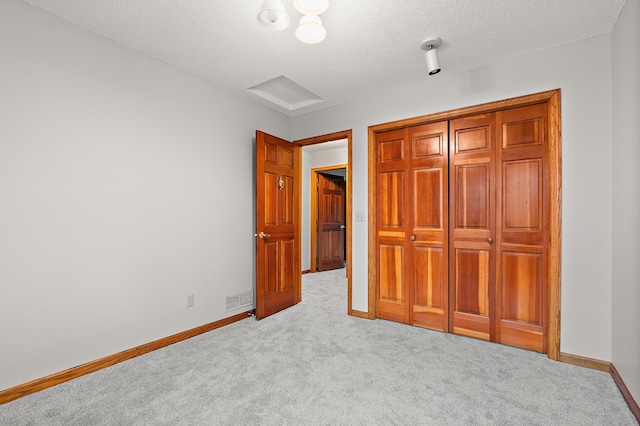 unfurnished bedroom featuring light colored carpet and a textured ceiling