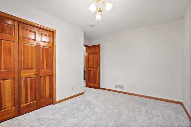 unfurnished bedroom featuring light colored carpet, a textured ceiling, and a closet