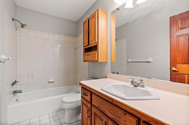 full bathroom featuring tile patterned floors, a textured ceiling, toilet, vanity, and tiled shower / bath