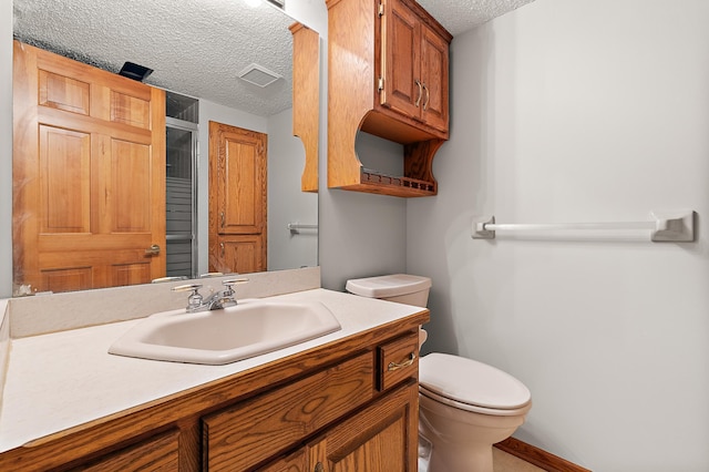 bathroom featuring vanity, an enclosed shower, a textured ceiling, and toilet