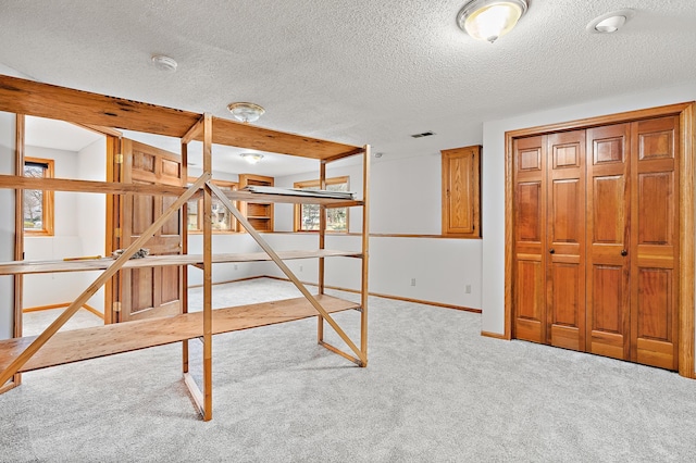 bedroom featuring light carpet, a closet, and a textured ceiling