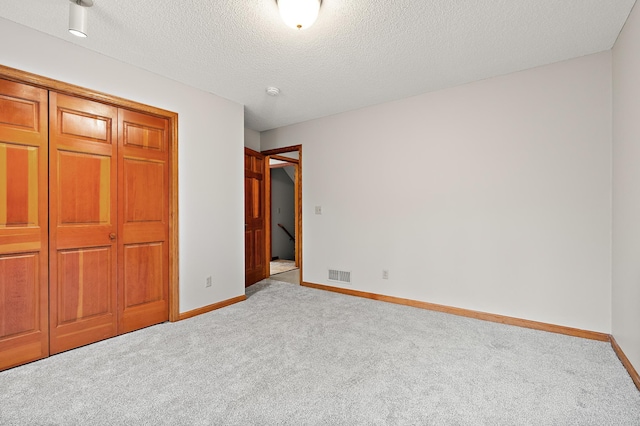 unfurnished bedroom with light carpet, a closet, and a textured ceiling