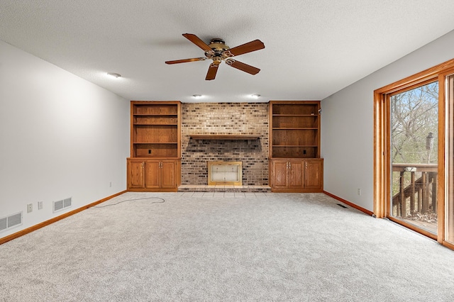 unfurnished living room with a fireplace, ceiling fan, light colored carpet, and a textured ceiling