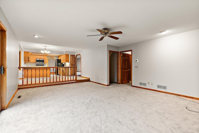 unfurnished living room with a textured ceiling, light carpet, and ceiling fan with notable chandelier