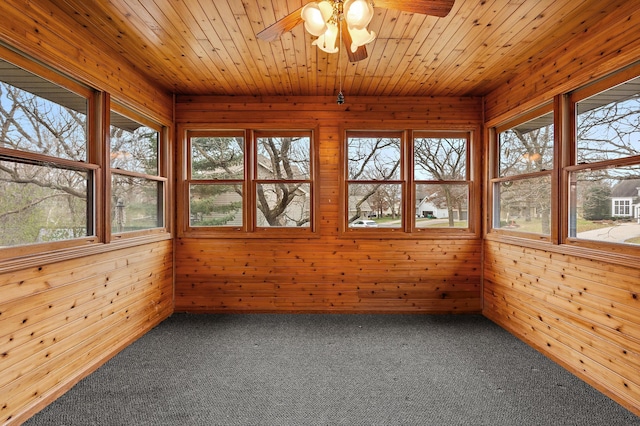 unfurnished sunroom featuring ceiling fan, plenty of natural light, and wood ceiling