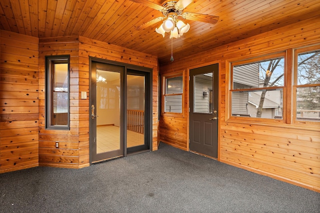 carpeted spare room with ceiling fan, wooden ceiling, and wood walls