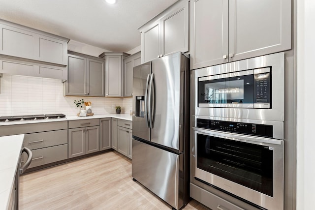 11728 35th St N, Lake Elmo, MN 55042 - kitchen with stainless steel appliances, gray cabinets, light countertops, decorative backsplash, and light wood-type flooring