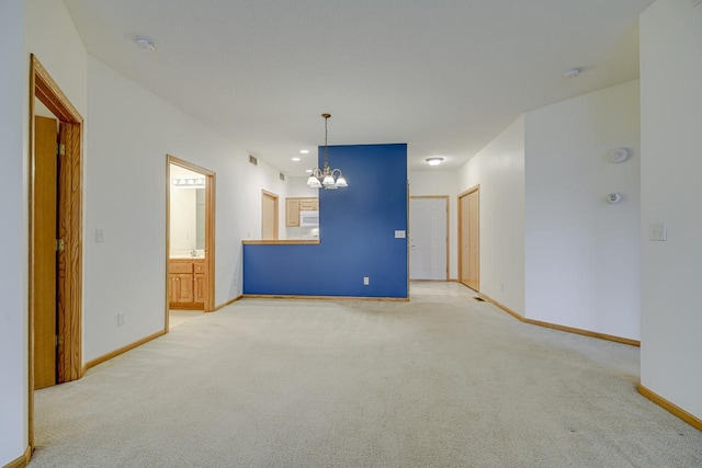 empty room featuring a chandelier and light carpet