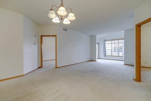 carpeted spare room featuring a notable chandelier