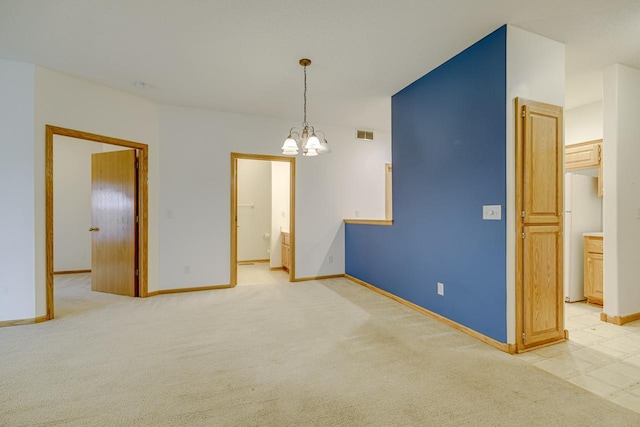 empty room with light colored carpet and a notable chandelier