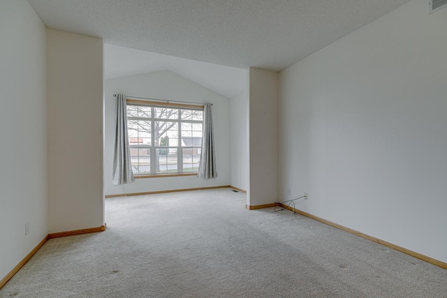 unfurnished room featuring vaulted ceiling, light carpet, and a textured ceiling