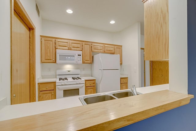 kitchen with light brown cabinetry, white appliances, and sink