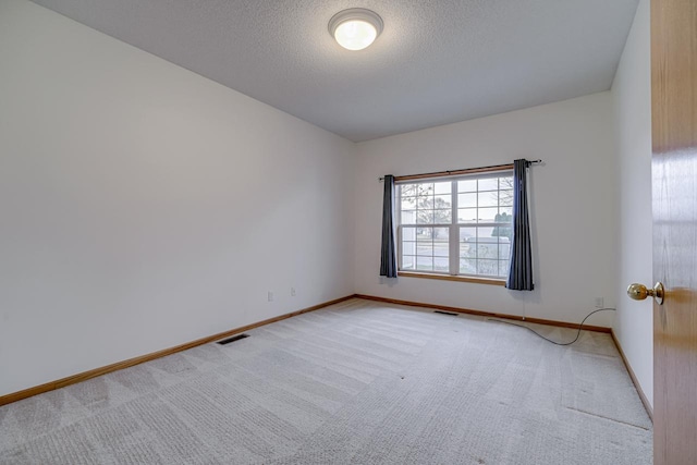 unfurnished room with light colored carpet and a textured ceiling