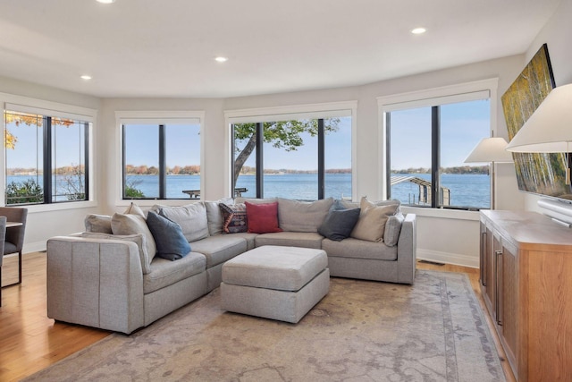 living room with a wealth of natural light, a water view, and light hardwood / wood-style floors