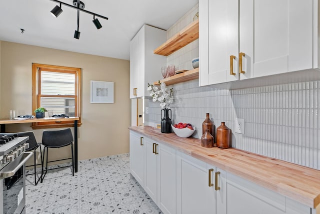 kitchen with high end stainless steel range oven, white cabinets, decorative backsplash, and wood counters