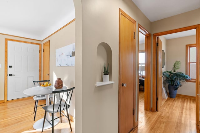 hall with a wealth of natural light and light hardwood / wood-style floors