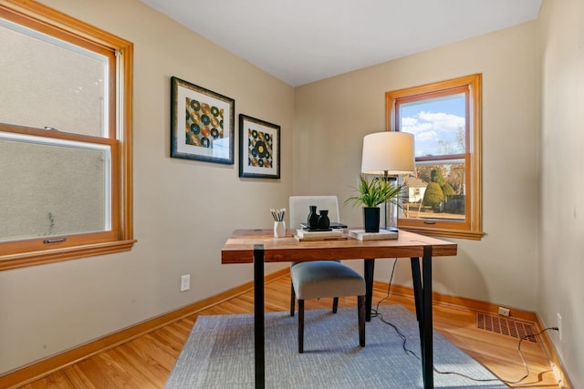 home office with light hardwood / wood-style flooring