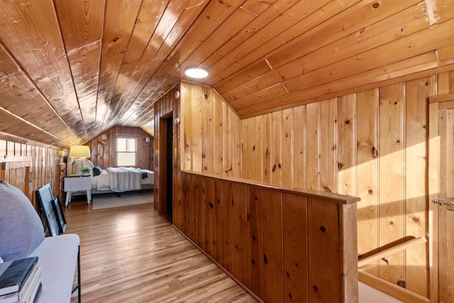 unfurnished bedroom featuring lofted ceiling, wooden walls, wooden ceiling, and light hardwood / wood-style floors