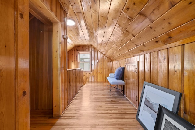 additional living space featuring light wood-type flooring, wooden walls, vaulted ceiling, and wooden ceiling