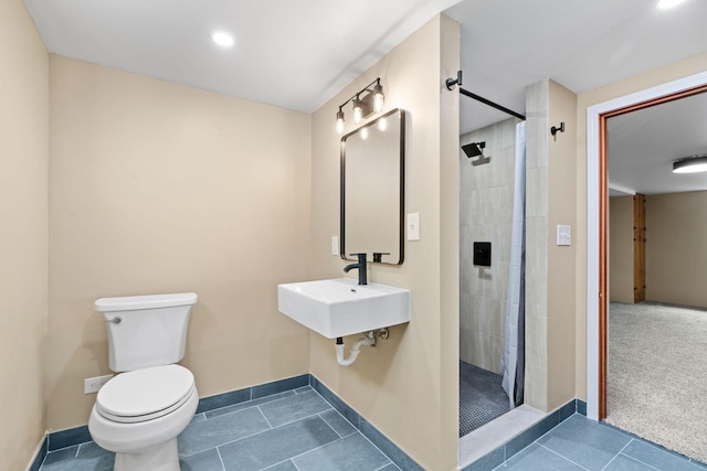 bathroom featuring toilet, sink, tile patterned floors, and a tile shower