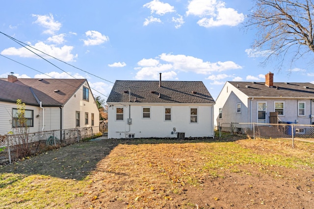 rear view of house with central AC unit and a lawn