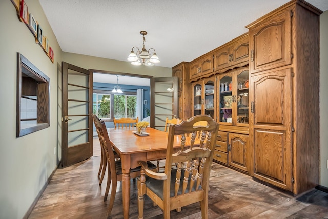 dining area with a chandelier, a textured ceiling, and dark wood-type flooring