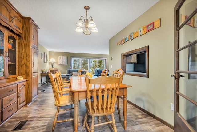 dining room with dark hardwood / wood-style flooring and an inviting chandelier