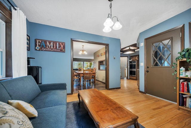 living room featuring hardwood / wood-style flooring, vaulted ceiling, and a notable chandelier