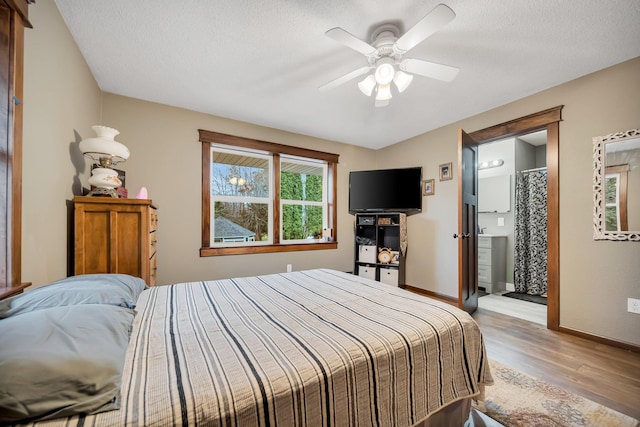 bedroom with ceiling fan, hardwood / wood-style floors, ensuite bathroom, and a textured ceiling