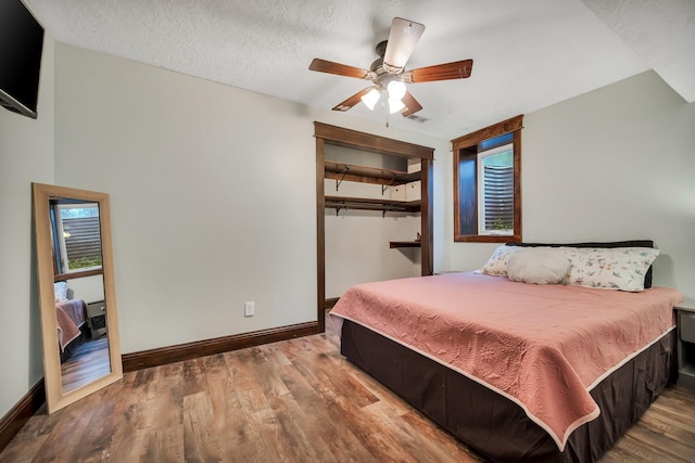 bedroom featuring a closet, ceiling fan, wood-type flooring, and a textured ceiling