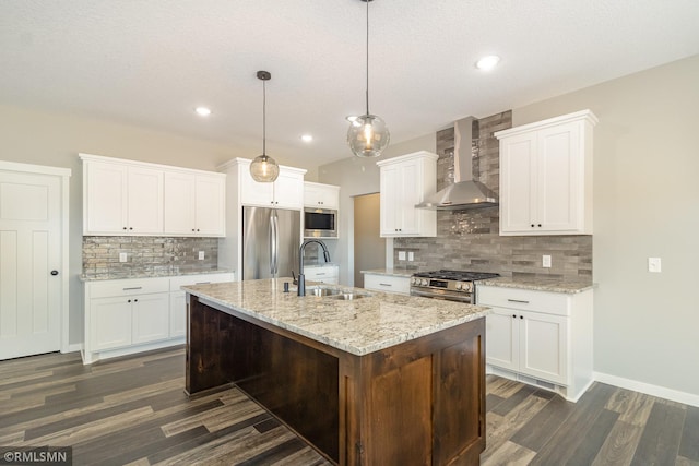 kitchen featuring white cabinetry, appliances with stainless steel finishes, wall chimney range hood, and decorative light fixtures