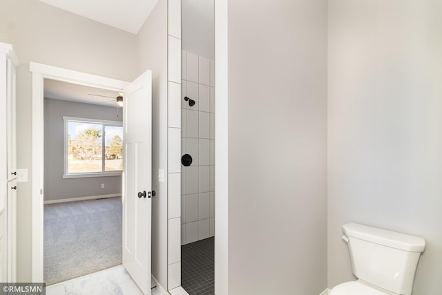 bathroom featuring a tile shower, ceiling fan, and toilet