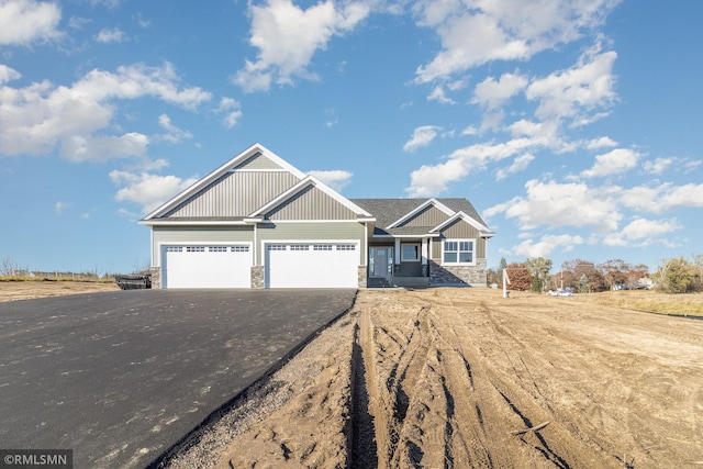 craftsman-style house with board and batten siding, a garage, stone siding, and aphalt driveway