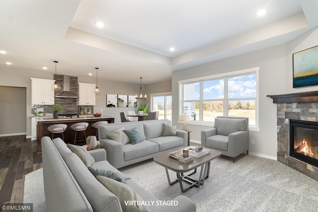 living room with baseboards, recessed lighting, and a raised ceiling