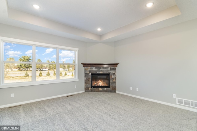 unfurnished living room with baseboards, a tray ceiling, carpet flooring, and visible vents