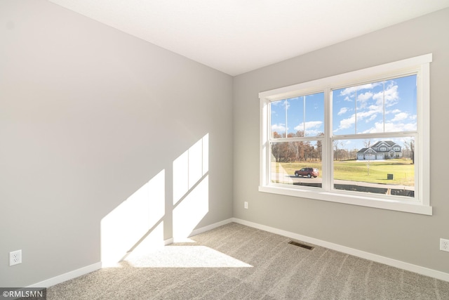 empty room featuring baseboards, visible vents, and light colored carpet