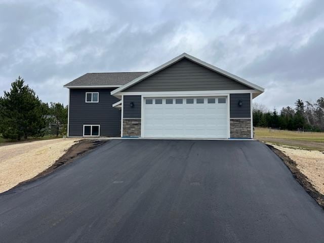 1320 Whiting Rd NW Unit 19, Bemidji, MN 56601 - view of front facade with asphalt driveway, stone siding, and a garage