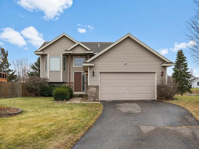 view of front of property with an attached garage, brick siding, fence, driveway, and a front lawn